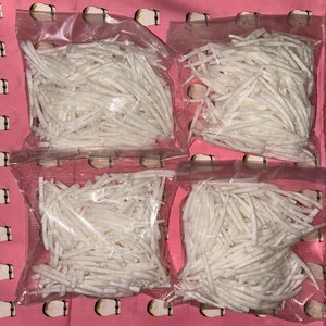 May include: Four clear plastic bags filled with thin, white, dried coconut strips.