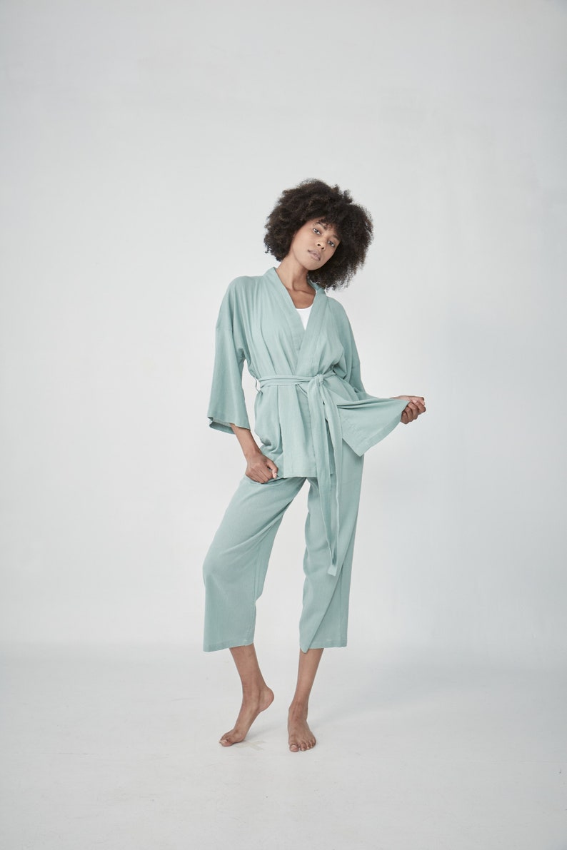 Model wearing a mint green matcha loungewear set, consisting of a wrap-style top with a side tie and three-quarter length sleeves, paired with comfortable, cropped pants.