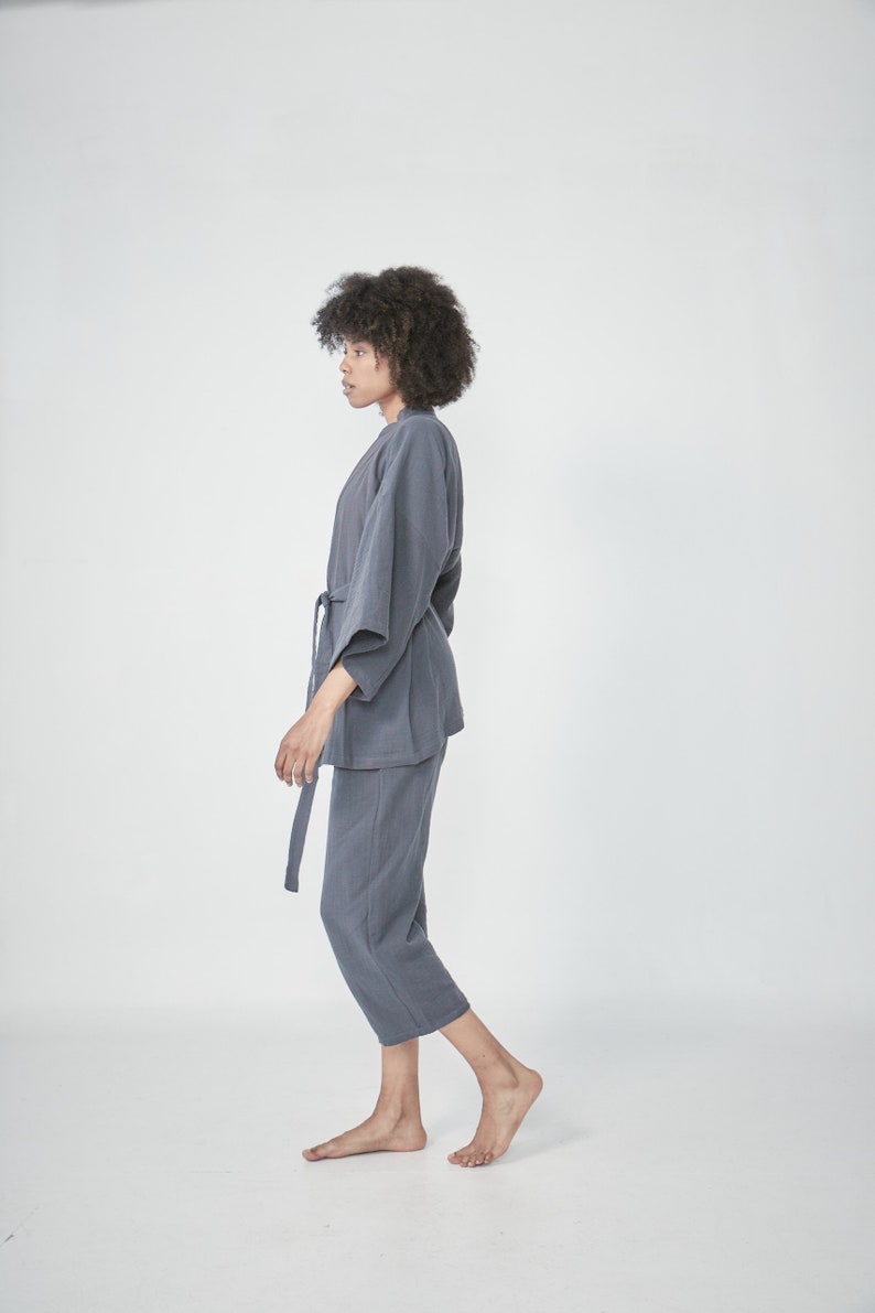 Model wearing a grey charcoal loungewear set, consisting of a wrap-style top with a side tie and three-quarter length sleeves, paired with comfortable, cropped pants.