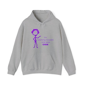 Puede incluir: Una sudadera con capucha gris con una ilustración de un palo de figura púrpura y el texto "I'm working toward one less CHIN".