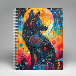 May include: A colorful spiral notebook with a black wolf silhouette on the cover. The wolf is surrounded by a vibrant pattern of circles, dots, and swirls in shades of blue, red, yellow, and green. The background is a dark blue with a hint of orange.