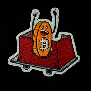 May include: Embroidered patch showing a cartoon Bitcoin coin with arms raised in a red roller coaster car. The coin has a smiling face and the Bitcoin symbol. The patch has a white border against a black background.