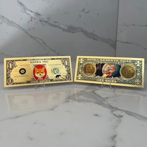 Peut inclure: Deux billets fantaisie de couleur or. L'un présente un logo Shiba Inu sur un cercle rouge, le texte "SHIBA INU" et "ONE SHIBA". L'autre billet représente un Shiba Inu dans l'espace et le texte "ONE SHIBA".