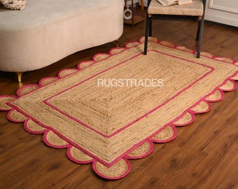 May include: A natural fiber rug with a pink scalloped border. The rug is made of jute and has a natural, earthy look. The rug is perfect for adding a touch of warmth and style to any room.