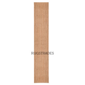 May include: A natural fiber runner rug in a light brown color. The rug is made of jute and has a woven texture. The rug is approximately 2.5 feet wide and 8 feet long. The rug is perfect for adding a touch of natural beauty to any room.