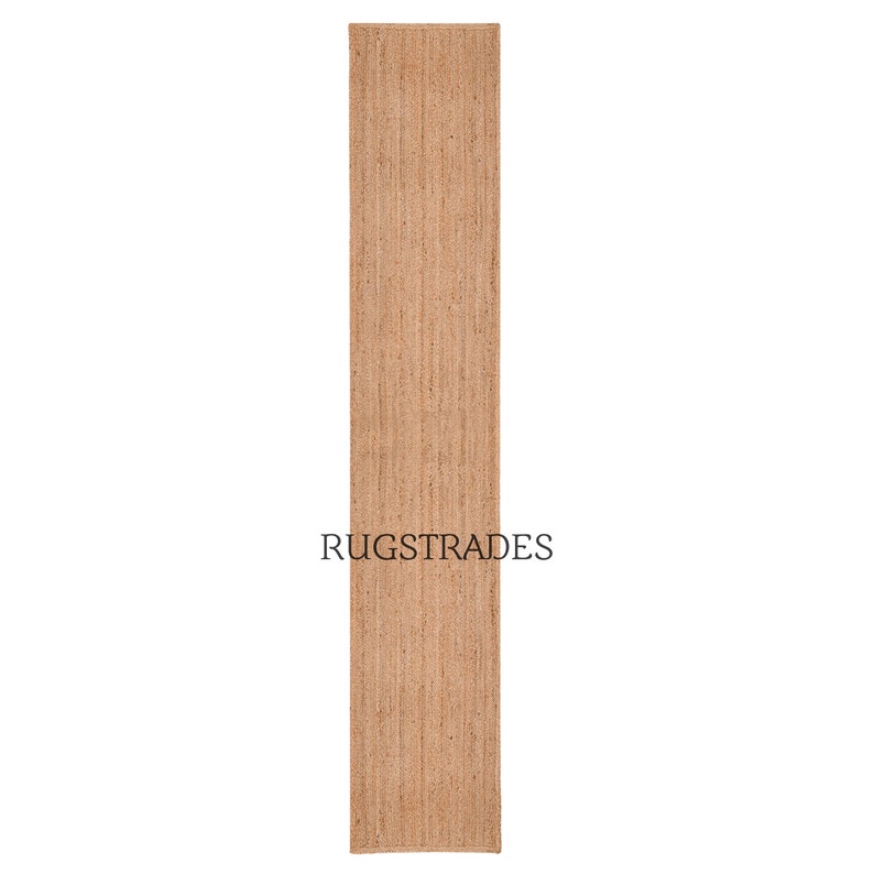 May include: A natural fiber runner rug in a light brown color. The rug is made of jute and has a woven texture. The rug is approximately 2.5 feet wide and 8 feet long. The rug is perfect for adding a touch of natural beauty to any room.