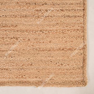 Pu&ograve; includere: Un tappeto in fibra naturale realizzato in juta, un materiale sostenibile e resistente. Il tappeto ha una trama tessuta e un colore marrone chiaro.