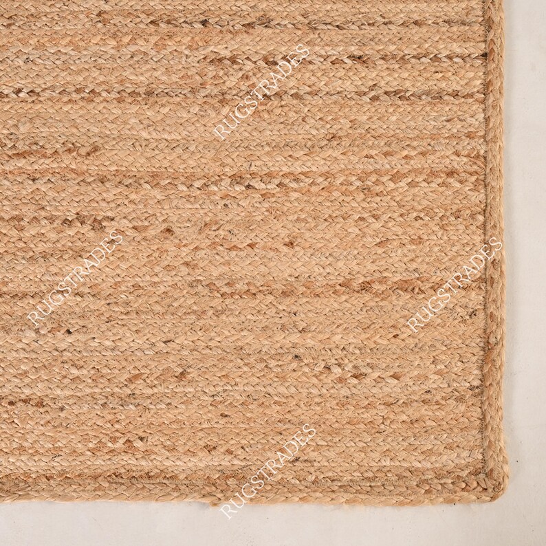 Pu&ograve; includere: Un tappeto in fibra naturale realizzato in juta, un materiale sostenibile e resistente. Il tappeto ha una trama tessuta e un colore marrone chiaro.