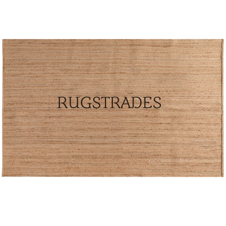 May include: A natural fiber rug with a woven texture in a light brown color. The rug has the text "RUGSTRADES" printed in black.
