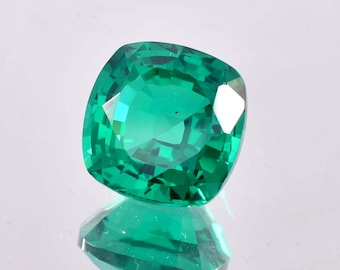 May include: A vibrant green emerald gemstone with a cushion cut. The gemstone is faceted and has a high level of brilliance.