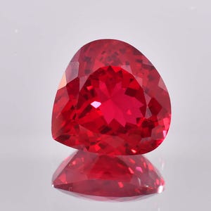Könnte beinhalten: Ein leuchtend roter Edelstein mit Herzschliff. Der Edelstein ist facettiert und hochglanzpoliert.