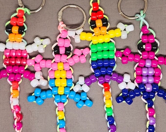 May include: Five colorful beaded keychains shaped like lizards. Each keychain is made with small, colorful beads and has a silver key ring attached.
