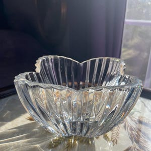 May include: A clear glass bowl with a fluted design. The bowl is shaped like a flower with multiple petals.