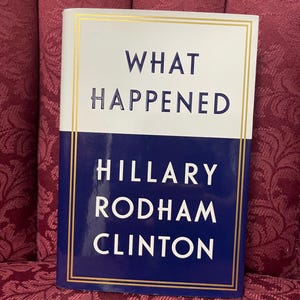 May include: A hardcover book titled "What Happened" by Hillary Rodham Clinton. The book cover is white with blue lettering and a gold border.