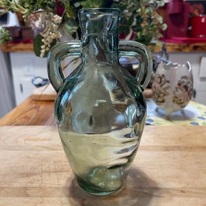 Ljusgrön vintageflaska, 18 cm hög med två handtag. Tjock, tung och robust. Unikt utseende med ojämn textur och några bubblor. Bra skick.