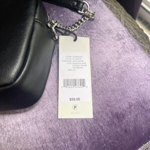 May include: Black crossbody bag with a diamond quilt pattern and studded top zip. The bag has a silver chain strap and a tag with the text "CF23EPUKTZ", "001 BLACK", and "SHINY SILVER".