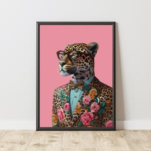 Puede incluir: Impresión artística enmarcada que presenta un leopardo con gafas, una camisa azul y una chaqueta con estampado floral. El leopardo tiene una pajarita y está sobre un fondo rosa. El marco es negro.