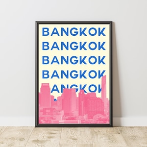 Puede incluir: L&aacute;mina enmarcada con la palabra "BANGKOK" en azul, repetida sobre un fondo amarillo claro. Un paisaje urbano rosa es visible en la parte inferior. El marco es negro.