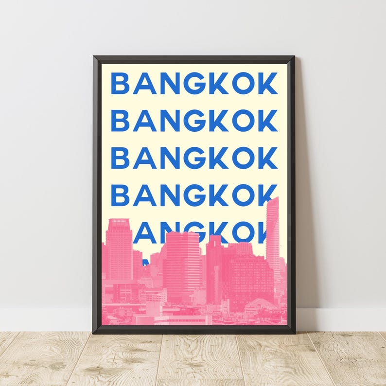 Puede incluir: L&aacute;mina enmarcada con la palabra "BANGKOK" en azul, repetida sobre un fondo amarillo claro. Un paisaje urbano rosa es visible en la parte inferior. El marco es negro.