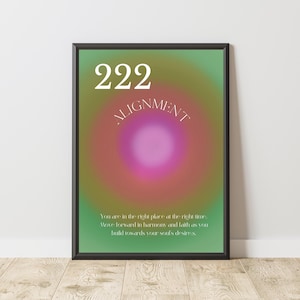 May include: A framed art print with a green, pink, and orange gradient background. The number "222" is at the top, with "ALIGNMENT" below it. The bottom of the print has text that reads, "You are in the right place at the right time."