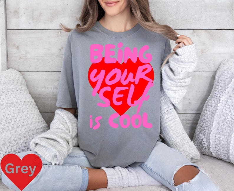 May include: A grey t-shirt with a pink and red heart graphic that says "Being Your Self is Cool".