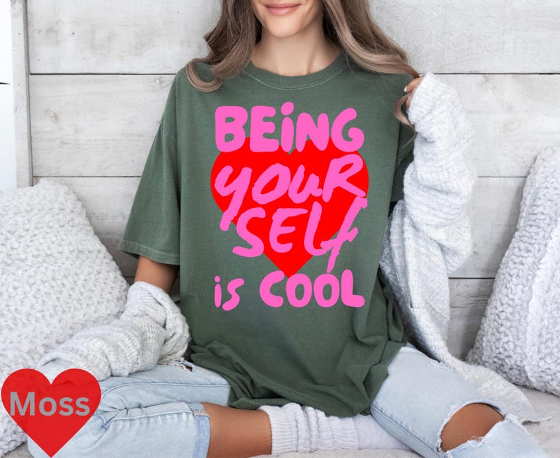 May include: A green t-shirt with the text "Being Your Self is Cool" in pink and red letters inside a pink heart.