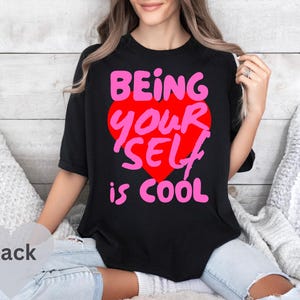 May include: Black t-shirt with a pink heart graphic and the text "Being Your Self is Cool".