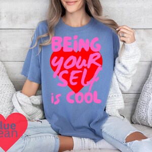 May include: A blue t-shirt with a pink and red heart graphic that says "Being Your Self is Cool".