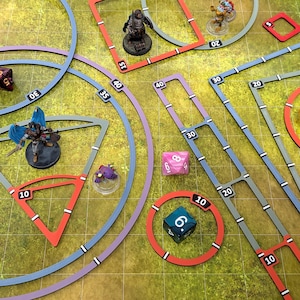 Könnte beinhalten: Ein Tisch-Rollenspiel-Setup mit einer grün-gelb gemusterten Oberfläche. Die Szene umfasst Miniaturfiguren, Würfel und Spielbrett-Elemente mit roten, blauen und grauen Linien und Zahlen. Die Würfel sind in verschiedenen Farben, darunter Pink, Orange und Blau.