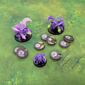 Peut inclure: Trois figurines miniatures d'insectes violets avec des ailes translucides et des accents verts, accompagnées de sept jetons de jeu circulaires présentant des symboles en spirale, une étoile, une icône de cube et des marquages numériques.