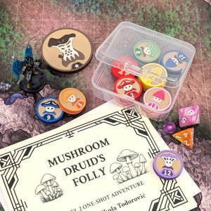 Może przedstawiać: Widok z góry na konfigurację gry RPG na stole. Zawiera miniaturową figurkę, żetony do gry z motywami grzybów, kości i przezroczysty plastikowy pojemnik. Obecny jest również podręcznik do gry zatytułowany "Mushroom Druid's Folly".