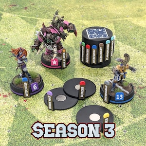 May include: A collection of fantasy miniature figurines, including a witch elf, star player, and linewoman, are arranged on a green and white game board. Black tokens and a cylindrical piece with character names are also present. The text "SEASON 3" is at the bottom.