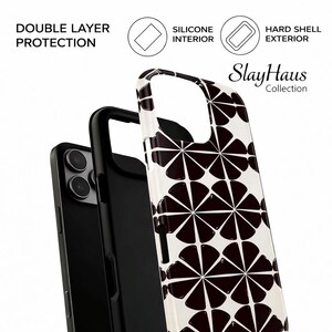 Puede incluir: Funda de tel&eacute;fono con estampado floral en blanco y negro con el texto "SlayHaus Collection". La imagen muestra las capas de la funda, destacando el interior de silicona y el exterior r&iacute;gido para una doble protecci&oacute;n.