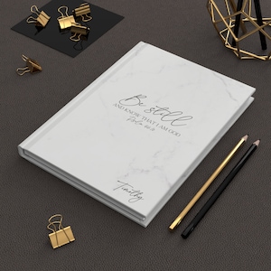 May include: White marble journal with the text "Be still and know that I am God, Psalm 46:10" and the name "Timothy" on the cover.