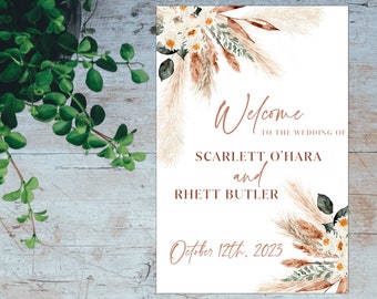 May include: A white wedding welcome sign with floral and pampas grass accents. The sign reads "Welcome to the Wedding of Scarlett O'Hara and Rhett Butler, October 12th, 2023."