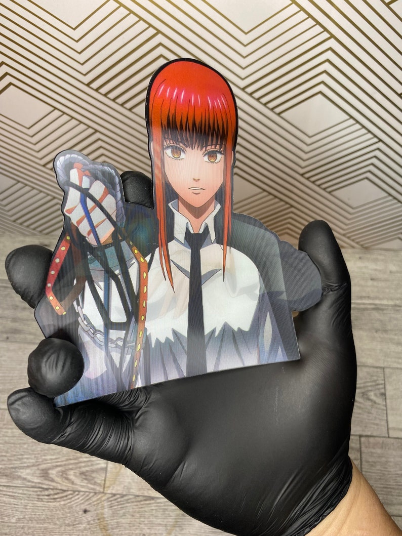 May include: A red-haired anime character with a white shirt and black tie, holding a chain with a silver charm. The character is depicted in a cartoon style.