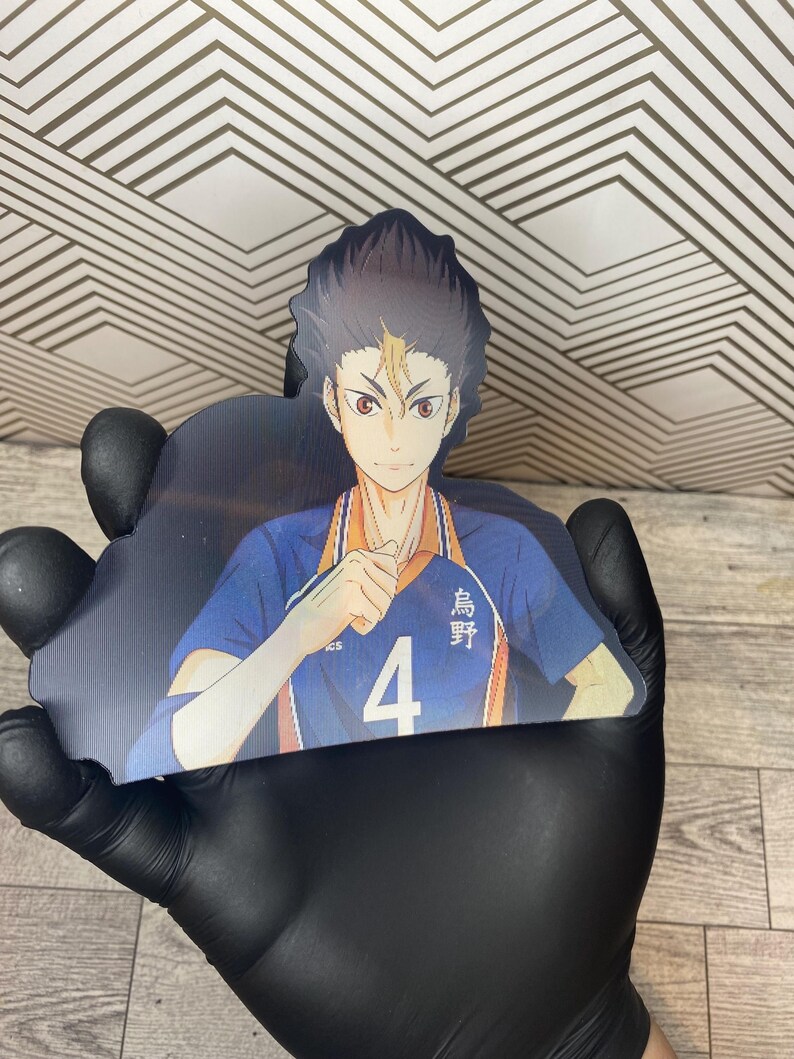 Puede incluir: Un personaje de anime con cabello negro y ojos marrones. El personaje lleva una camiseta azul y naranja con el n&uacute;mero 4 y el texto japon&eacute;s "烏野" en ella. El personaje est&aacute; levantando su mano derecha en un pu&ntilde;o.