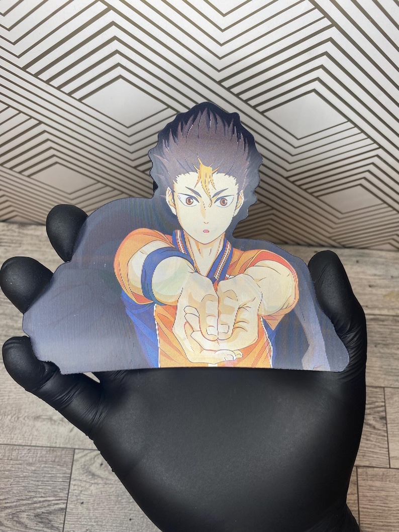 Puede incluir: Un personaje de anime en blanco y negro con ropa naranja y azul se representa en un primer plano. El personaje est&aacute; extendiendo su mano derecha, con los dedos extendidos, como para agarrar algo. El fondo est&aacute; desenfocado y parece ser una cancha deportiva.