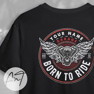 Pode incluir: Camiseta preta com um gráfico vermelho, branco e preto de um motor de motocicleta com asas. O gráfico diz "Your Name Garage Est 22 Born to Ride".