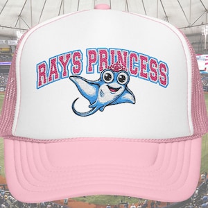 Könnte beinhalten: Rosa-weiße Trucker-Cap mit dem Text "RAYS PRINCESS" und einer Cartoon-Manta-Grafik. Die Kappe hat einen Mesh-Rücken und einen gebogenen Schirm. Text und Grafik sind in Blau und Rosa gehalten. Wahrscheinlich ein Fanartikel.