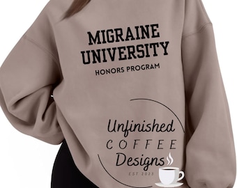 May include: A light brown sweatshirt with the text "Migraine University Honors Program" and a logo that says "Unfinished Coffee Designs Est 2023" with a coffee cup graphic.