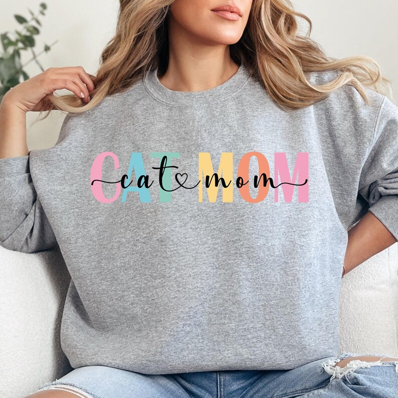 a woman sitting on a couch wearing a grey sweatshirt with the word catatonn
