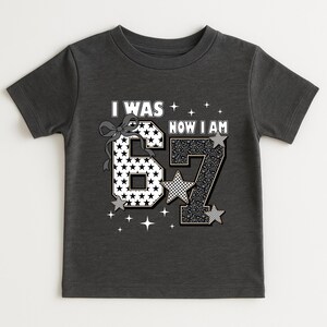 A bright and cheerful image of a girl wearing heart sunglasses and her special birthday shirt. The focus is on the shirt's message about growing up. The mix of patterns (stars, leopard, checks) makes it a unique piece of apparel. Parents looking for "7th birthday girl shirt" or "seven year old gift" will find this design appealing for its modern and cute aesthetic.