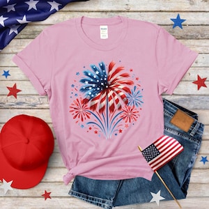 a pink t - shirt with a red, white, and blue fireworks on it