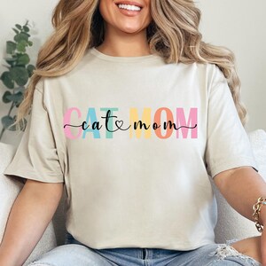 a woman sitting on a couch wearing a t - shirt that says eat mom