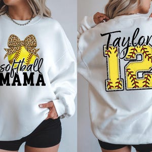 Rear view of the custom softball shirt showing the large back print. The number "12" is printed in a large, textured yellow font resembling a jersey. The name "Taylor" is written in a red script font across the top of the number.