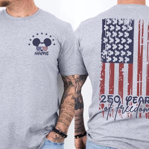 A gray t-shirt with a graphic design on the back, depicting an American flag and the text "250 YEARS OF FREEDOM" printed on it.