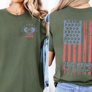 The image is a collage of two photos showing the back and front of a green t-shirt with a graphic design featuring an American flag and the text "250 YEARS OF FREEDOM".