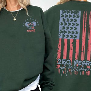 A green sweatshirt with a graphic design on the back, featuring an American flag and the text "250 YEARS OF FREEDOM".