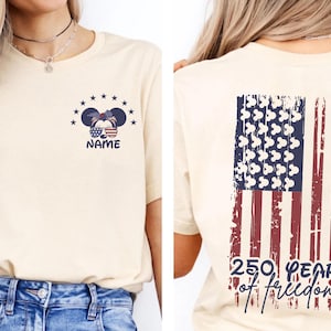 A woman wearing a beige t-shirt with a graphic design on the back, depicting an American flag and the text "250 YEARS OF FREEDOM".